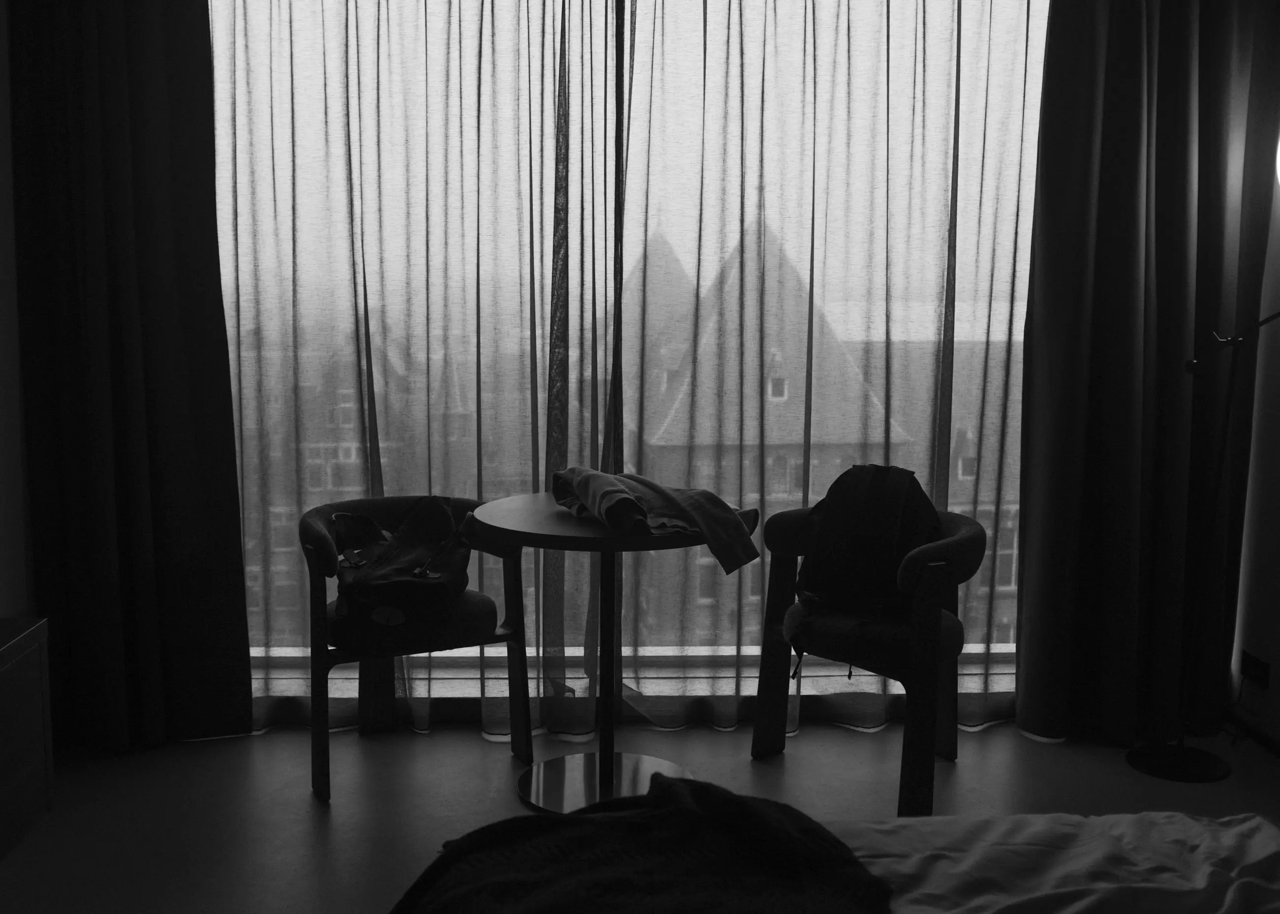 Two chairs and a small table in front of a curtained window, fog beyond