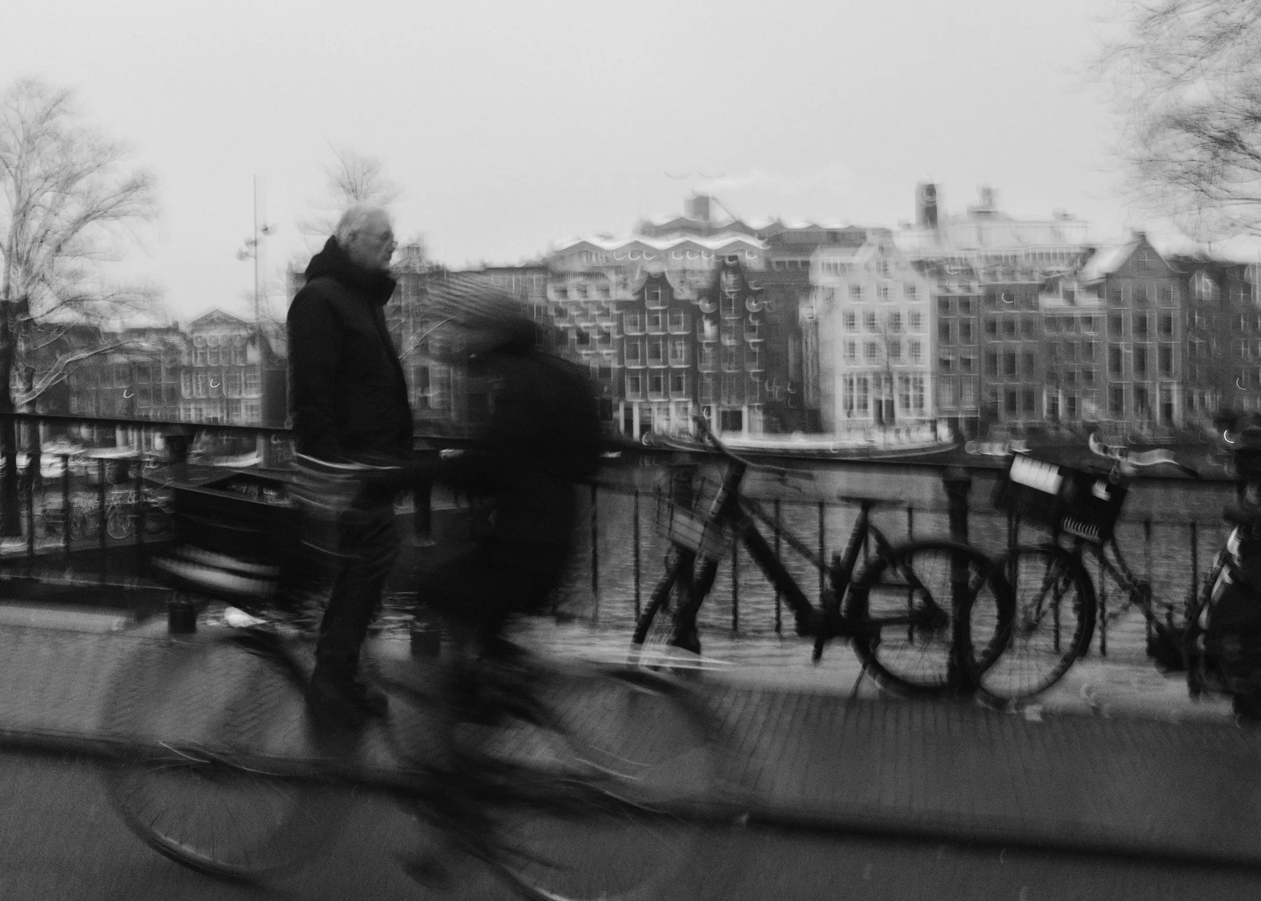 A cyclist and a pedestrian blurred against the Amstel