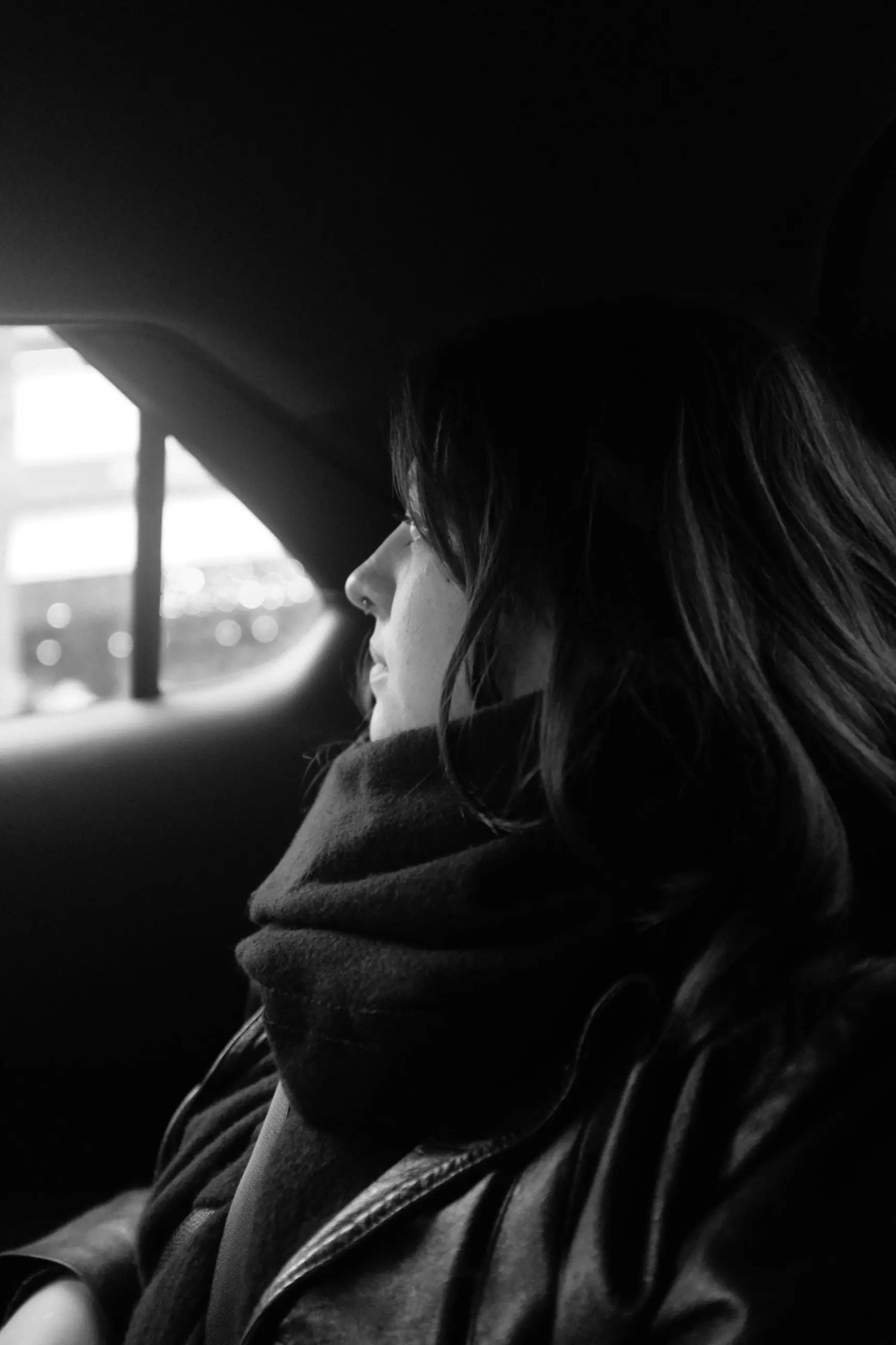 A woman in profile in the back of a taxi, looking out of the window