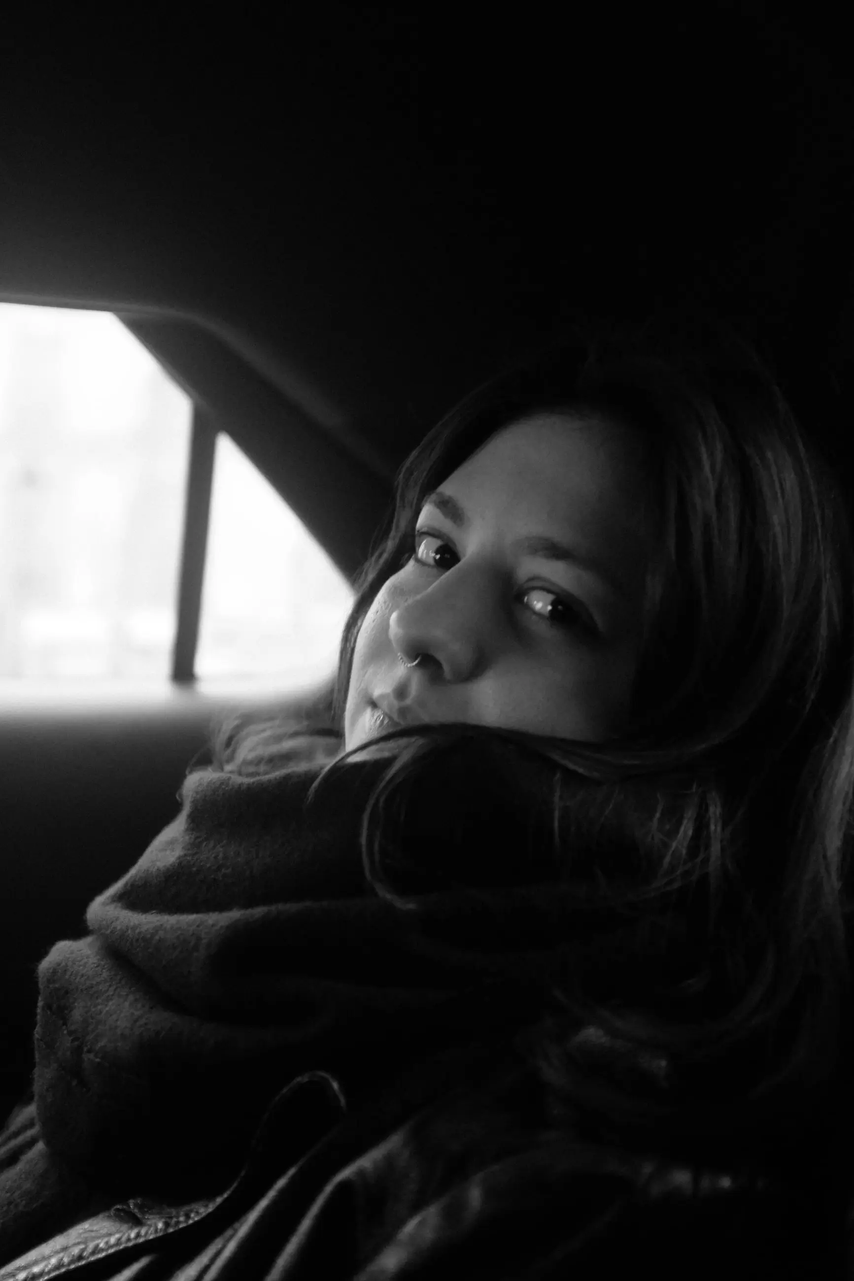A woman looks back over her shoulder, chin in her scarf
