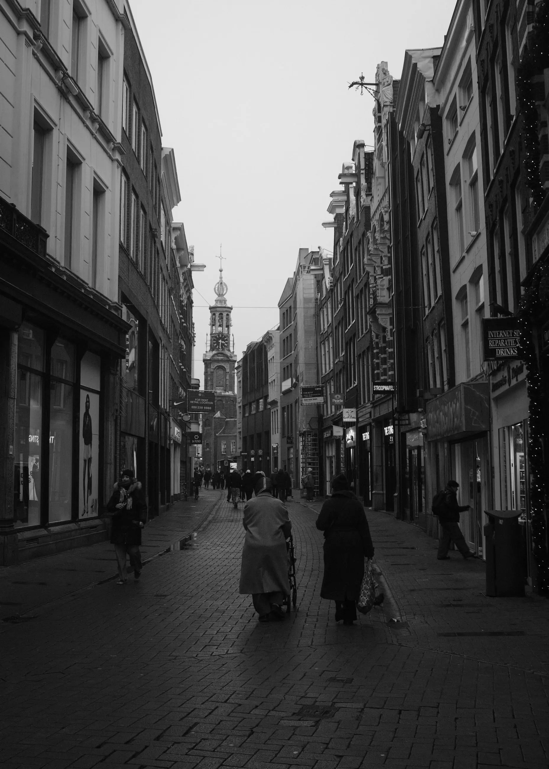 Pedestrians walking away along a cobbled shopping street