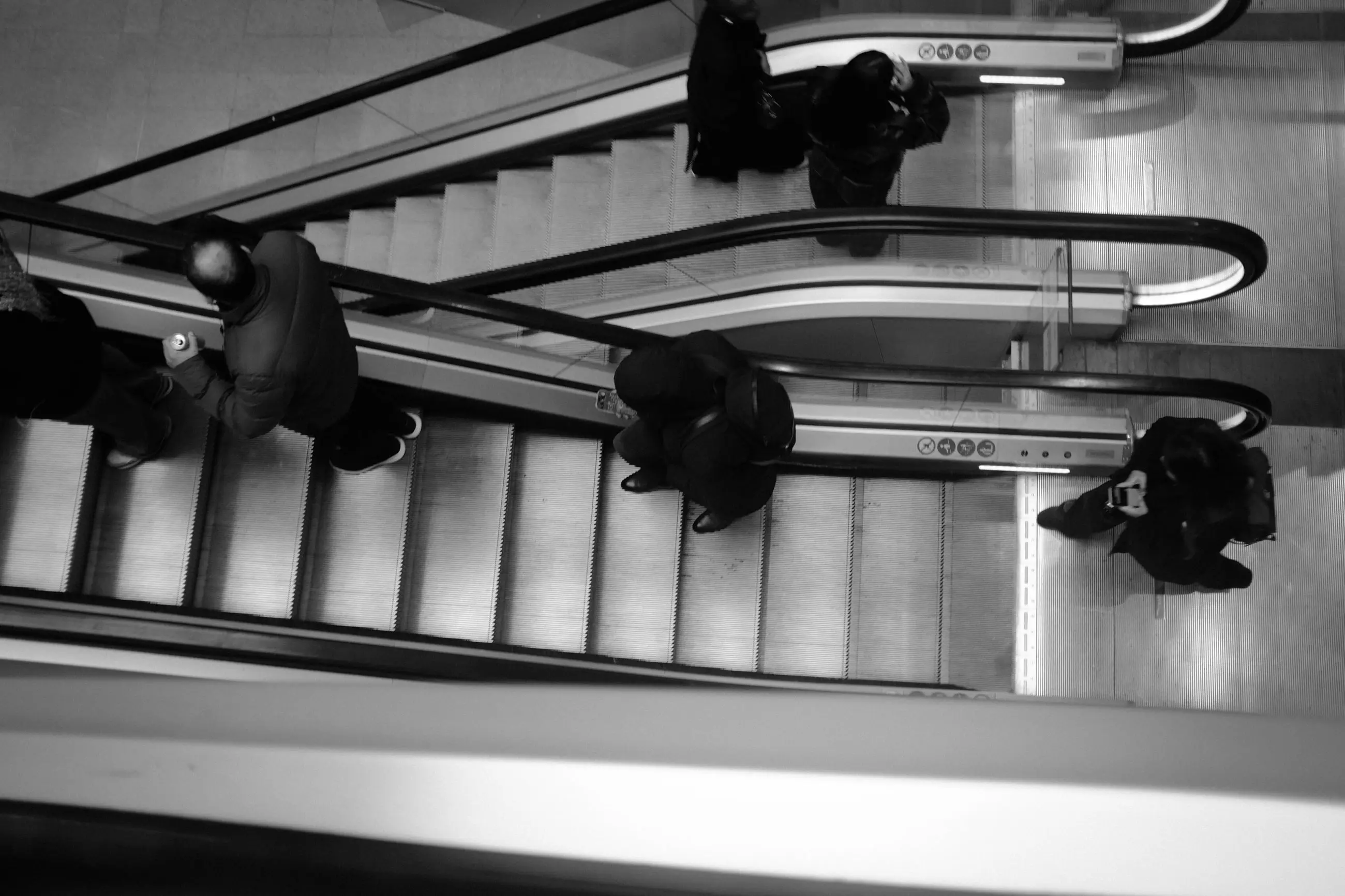 Escalators seen from above, commuters' heads and shoulders