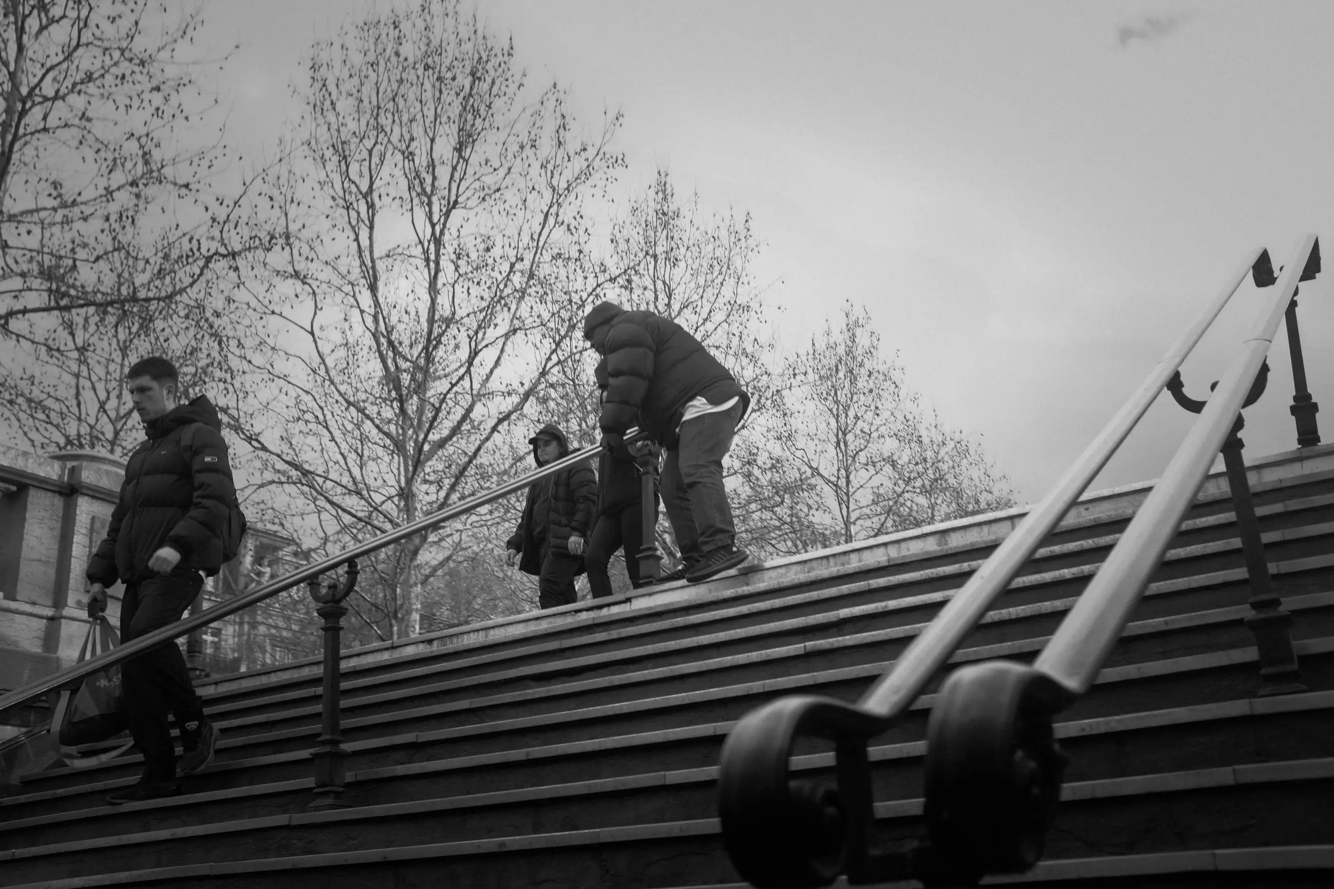 Men climbing the steps of the square, a handrail cutting across the frame