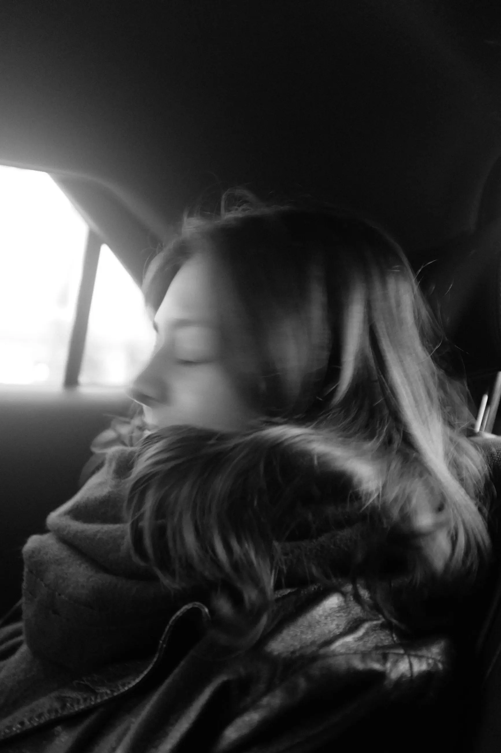 A woman with her eyes closed, face resting against her collar