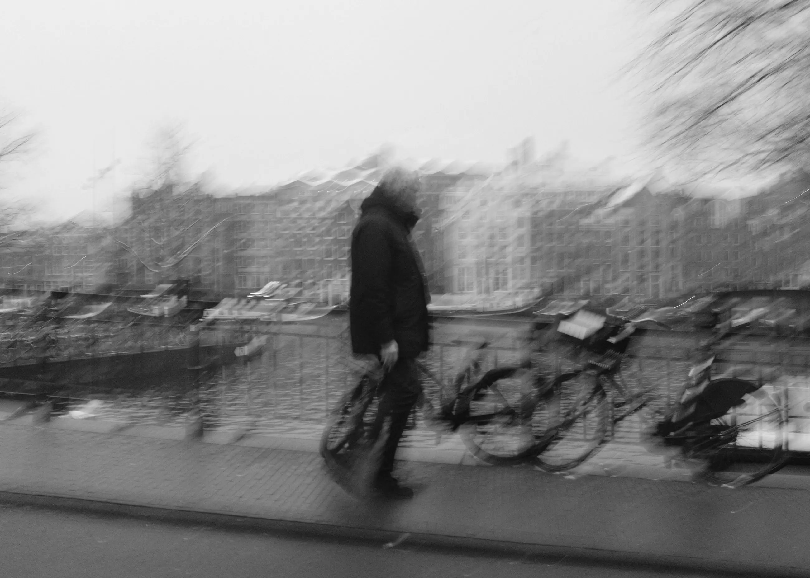 A walker blurred in front of bikes parked along a railing