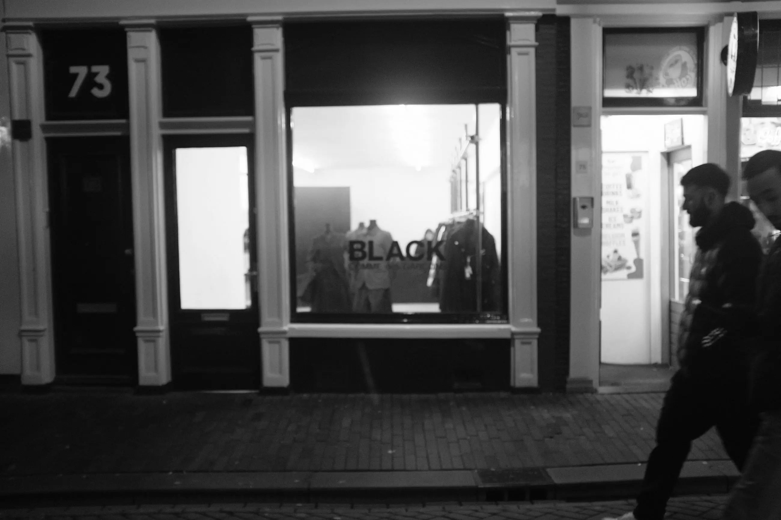 A lit window on a dark street, a man walking past