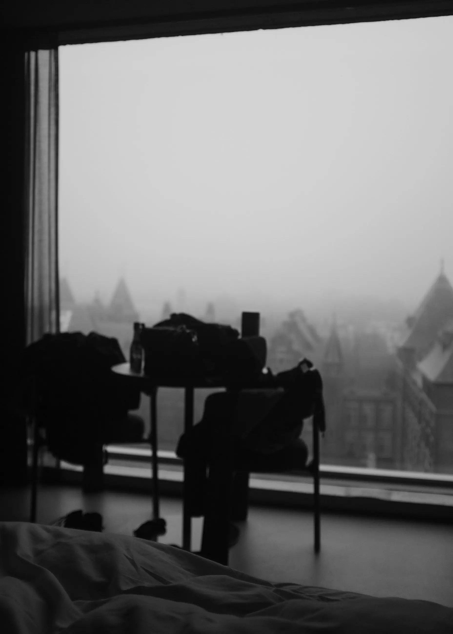 Chairs and bags in silhouette against a window full of fog