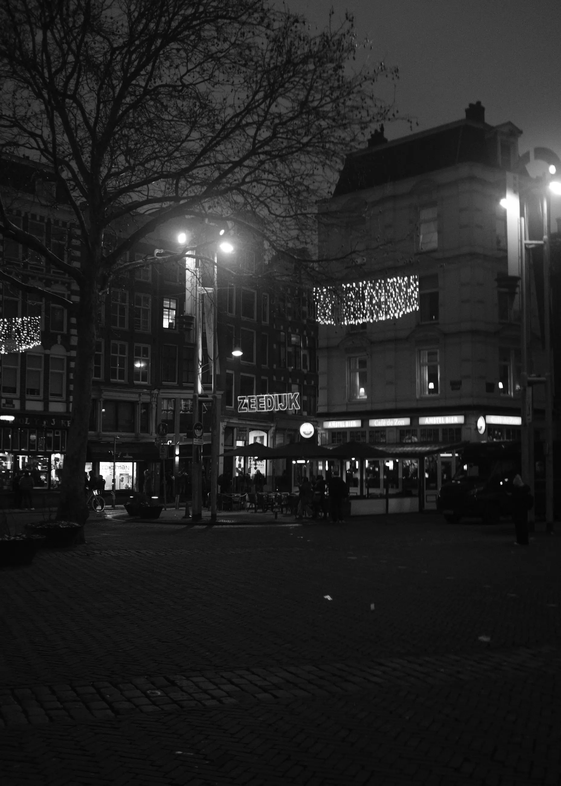 A night street under string lights, shopfronts glowing