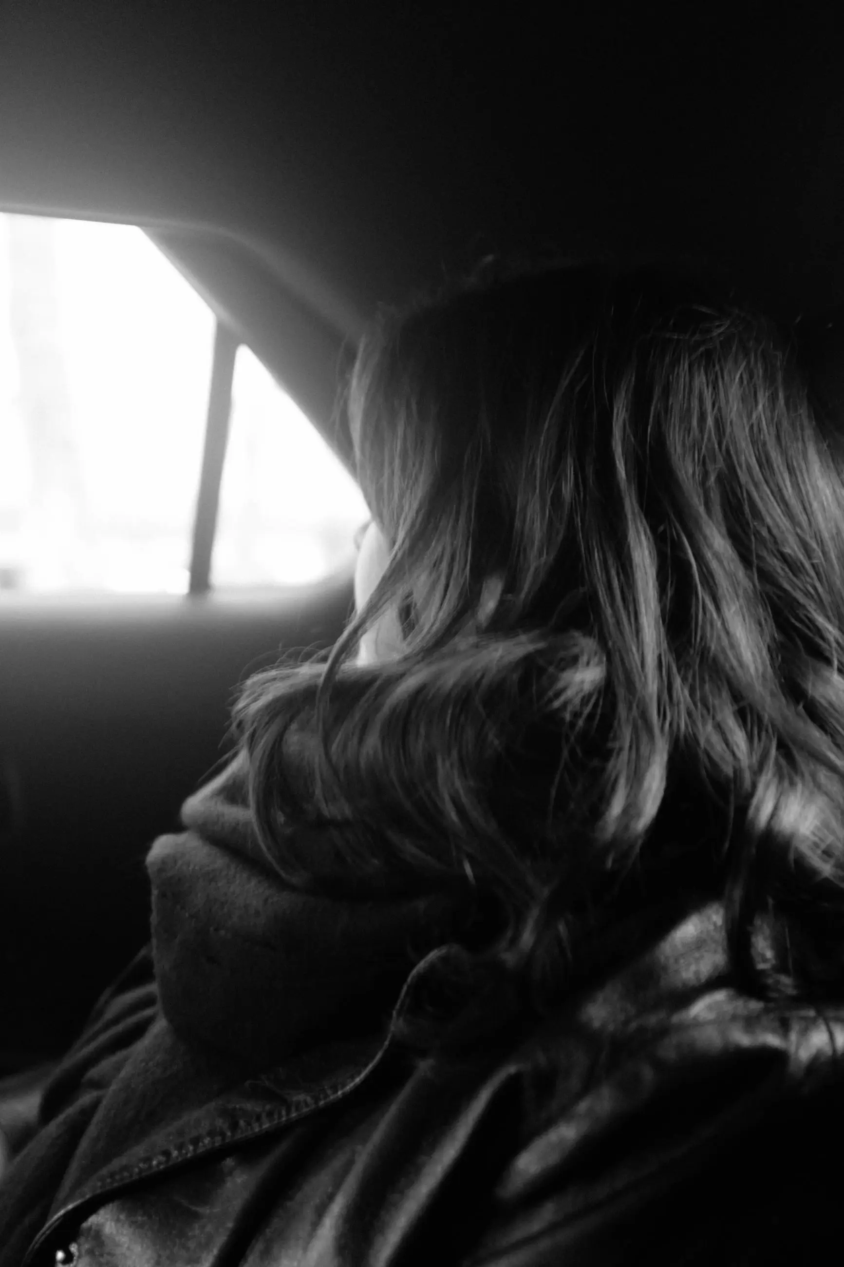 A woman in profile, hair falling over her scarf, looking out of the window