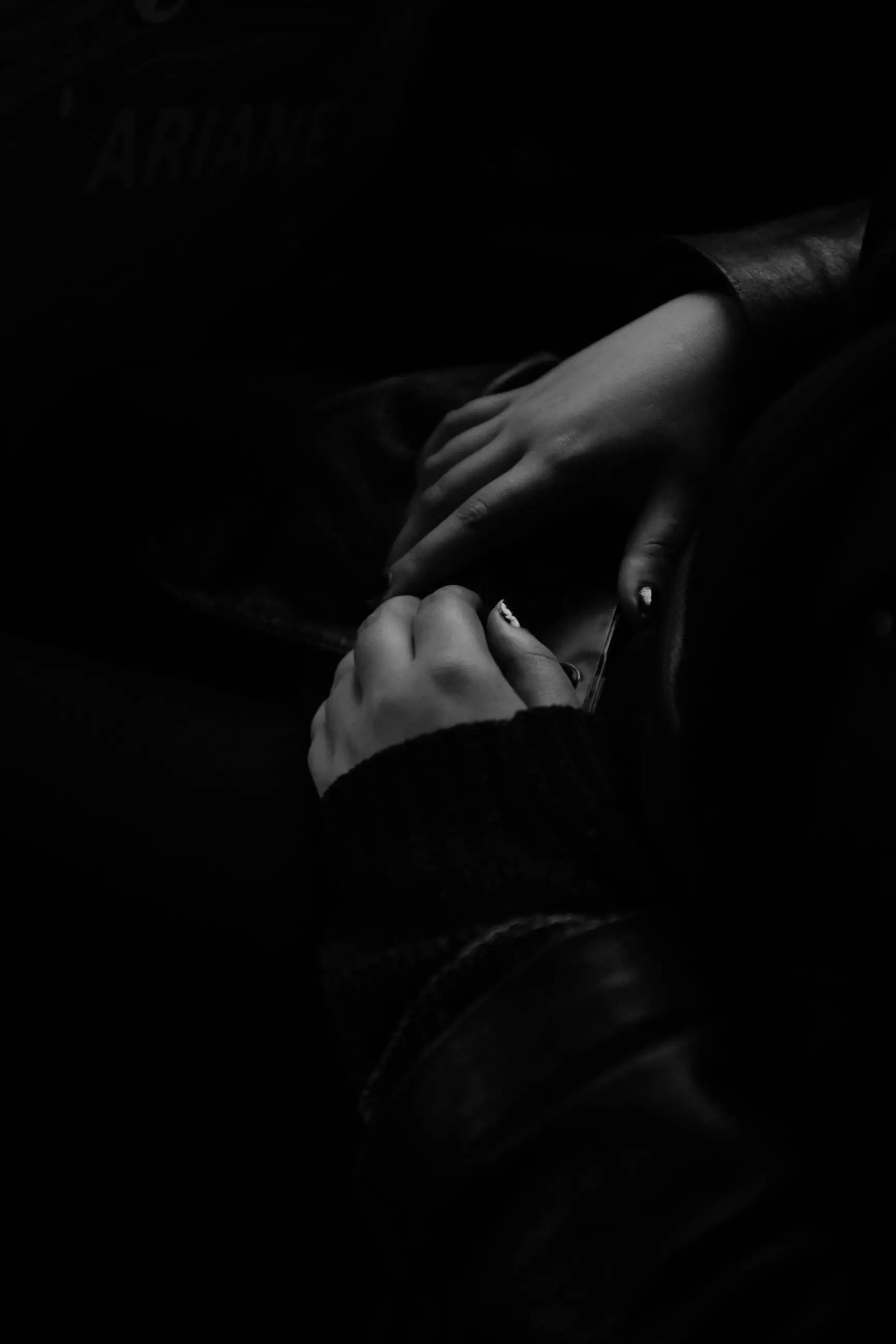 Two hands folded in the dark of the taxi, a leather sleeve at the edge of the frame