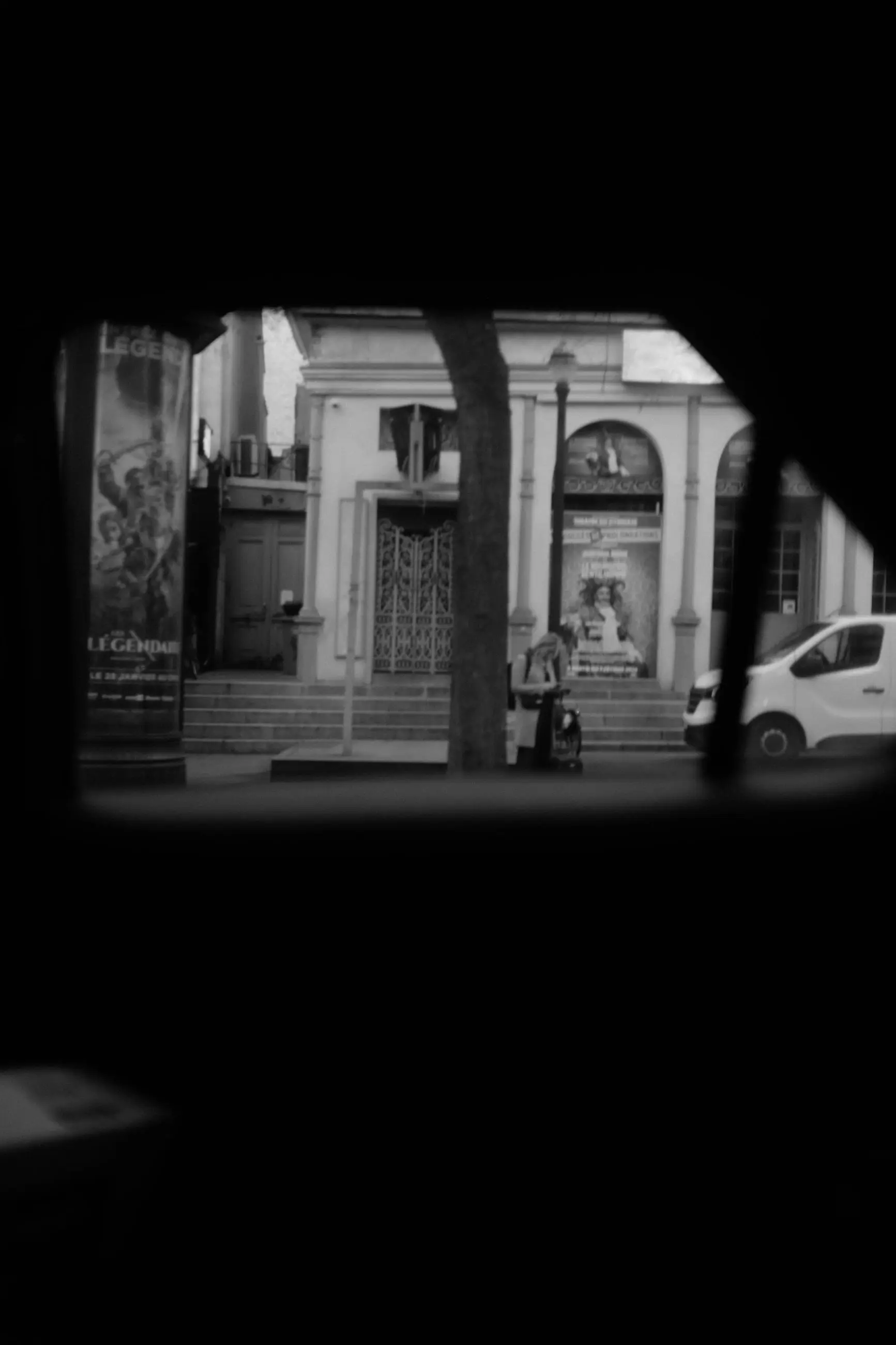 A small window of light onto a street corner, the rest of the frame black