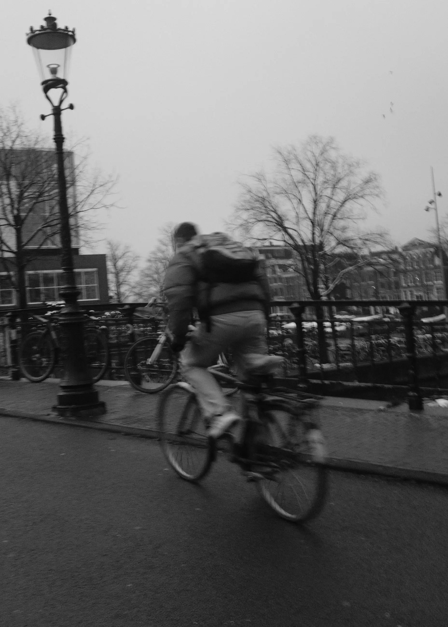 A cyclist with a backpack riding past a street lamp