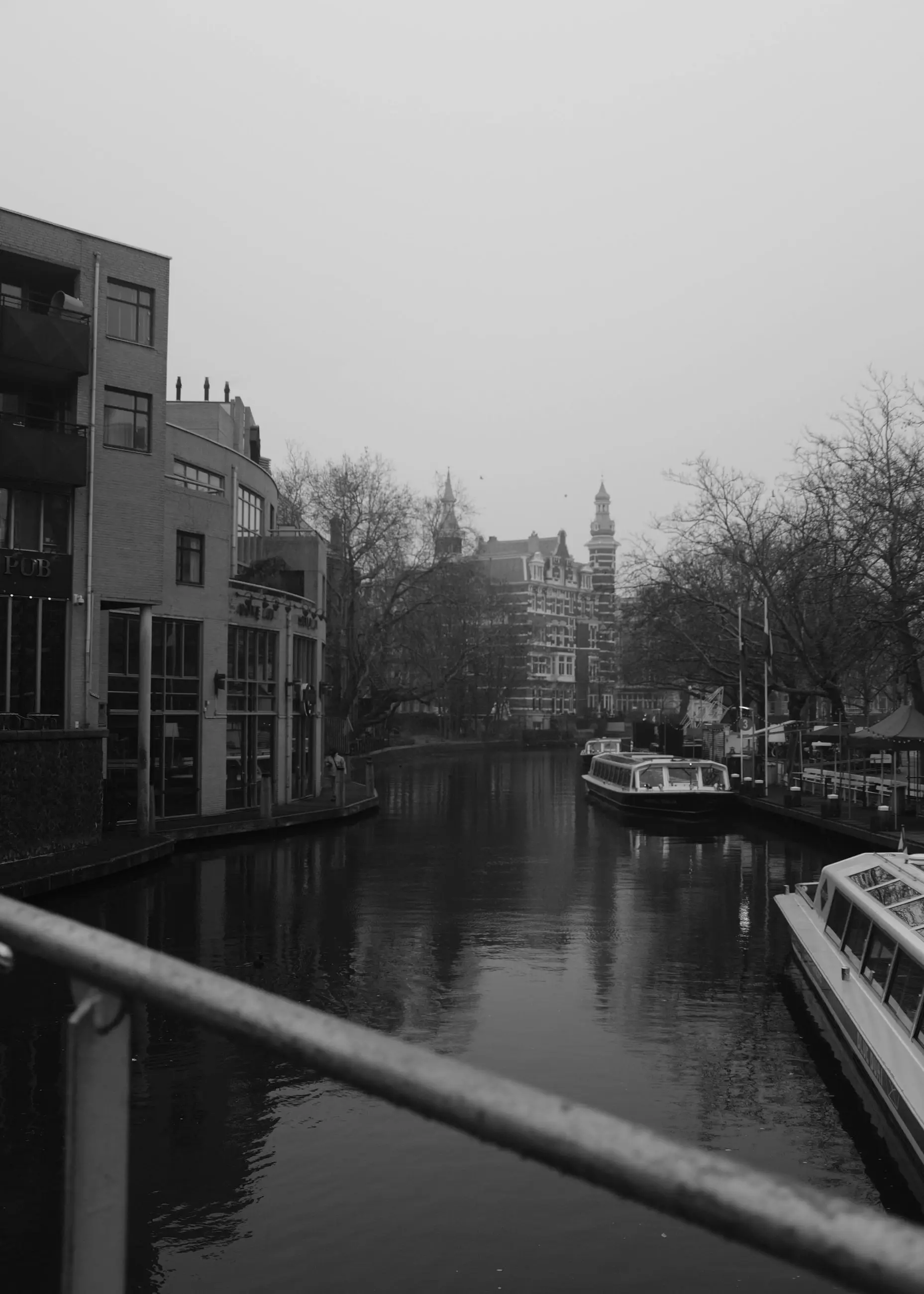 A canal in winter light, a railing in the foreground