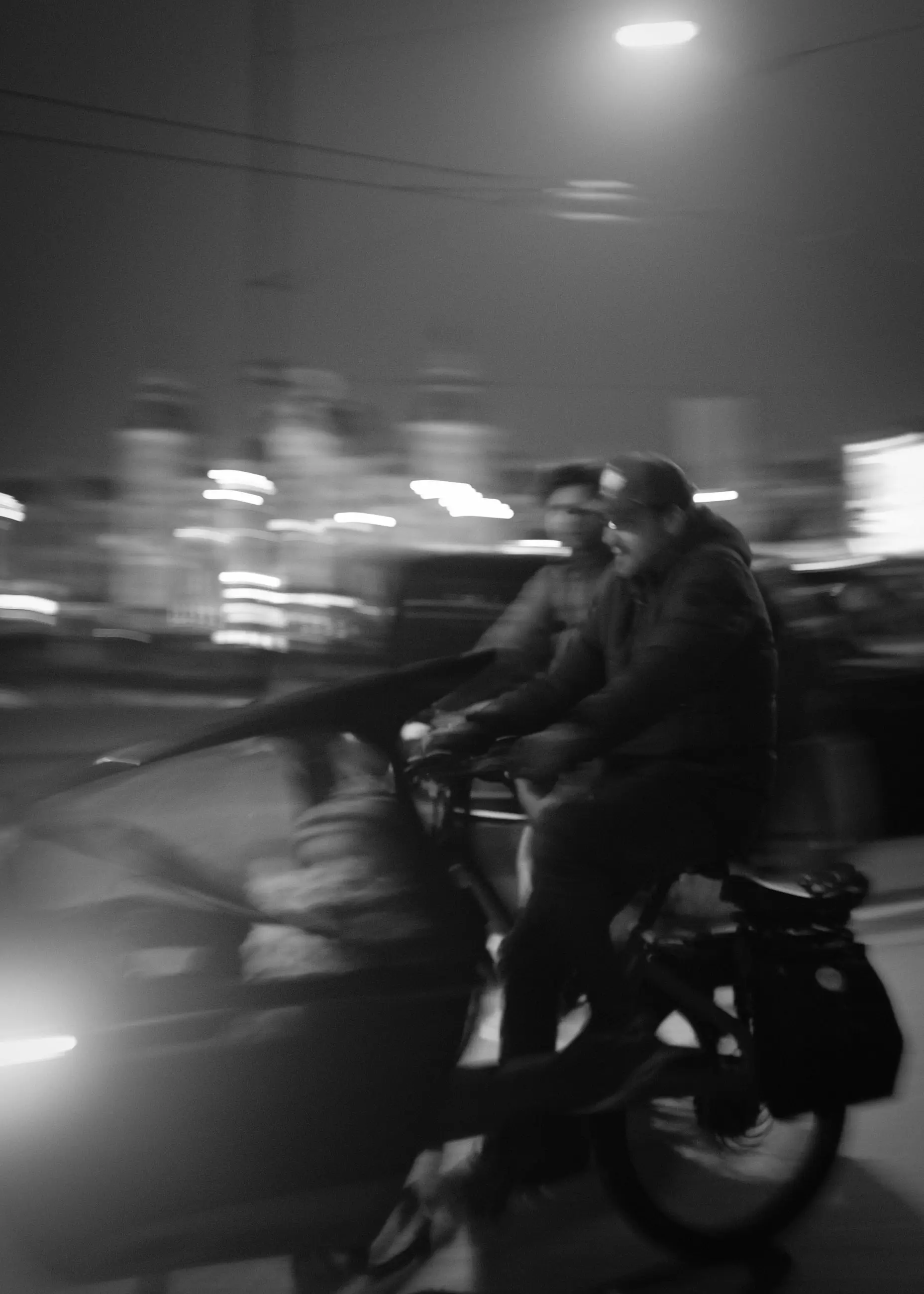 Two cyclists streaking through light on a night street