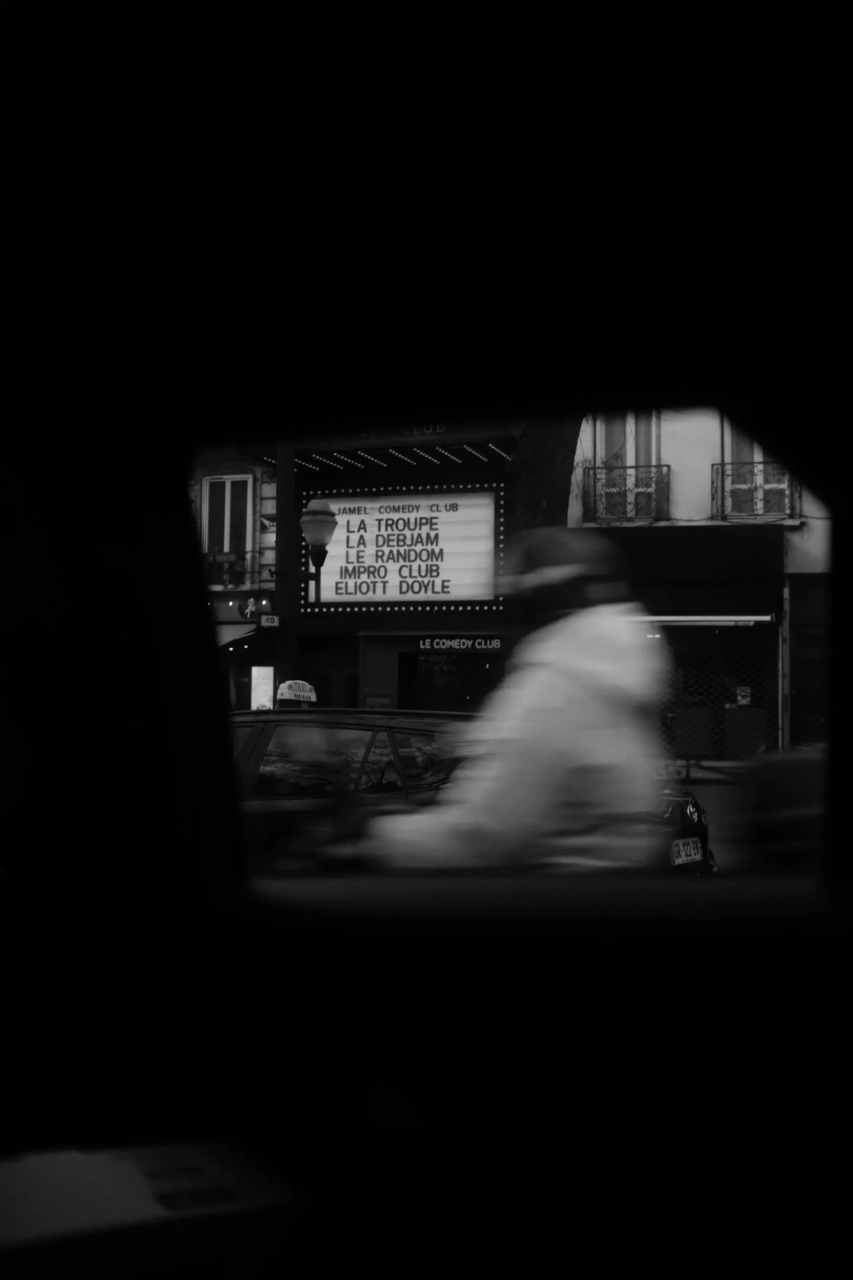 A passer-by blurred past a theatre sign in the taxi's dark window
