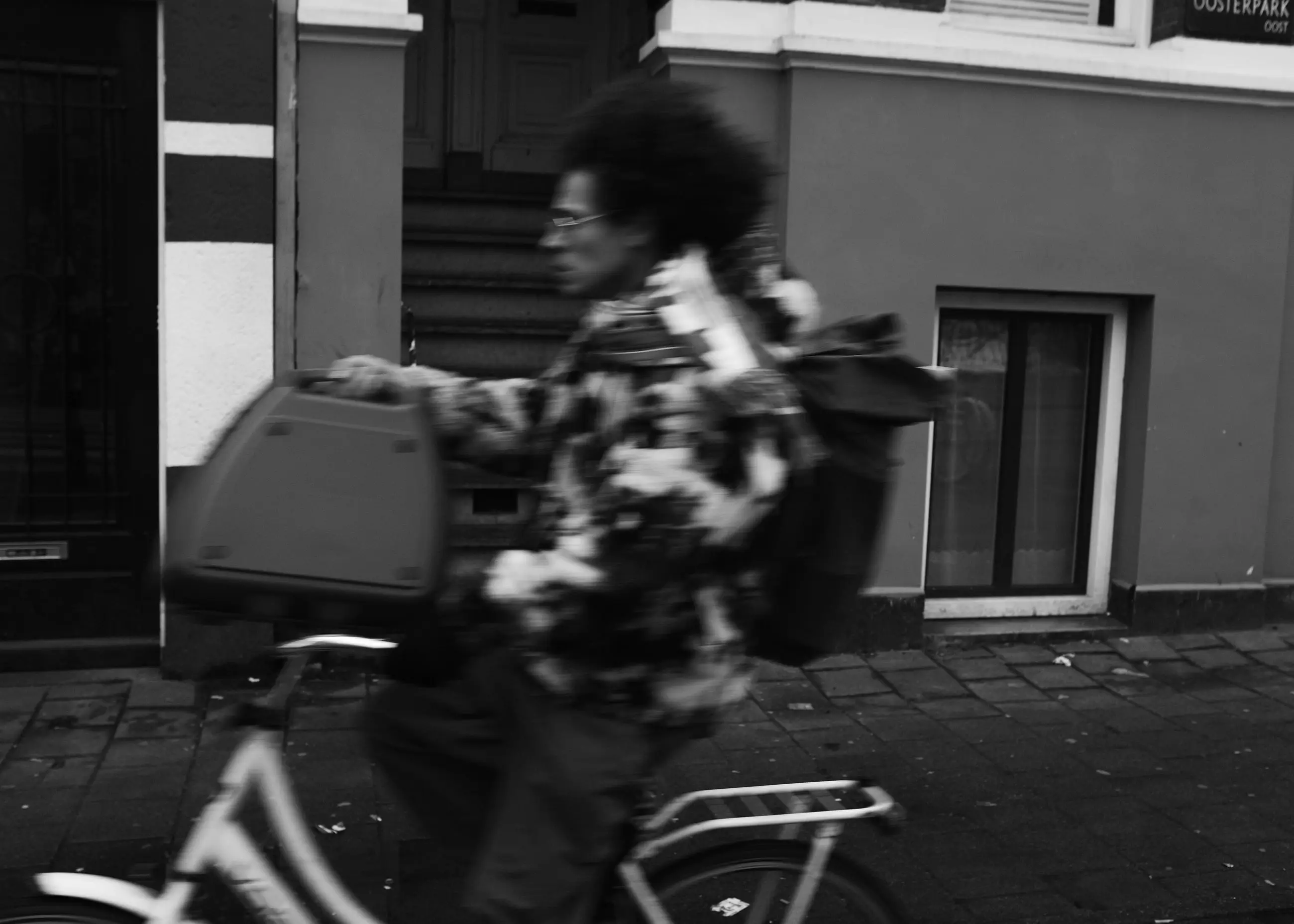 A cyclist in a patterned jacket blurred against a wall