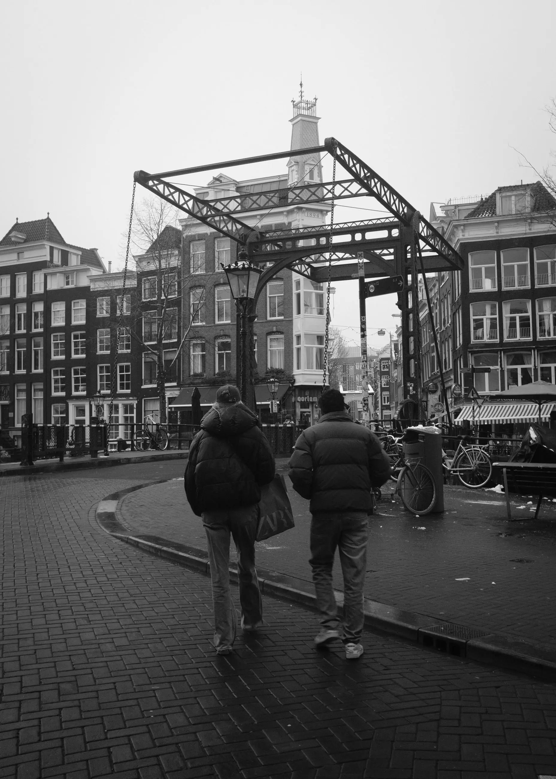 Two people walking toward an open drawbridge