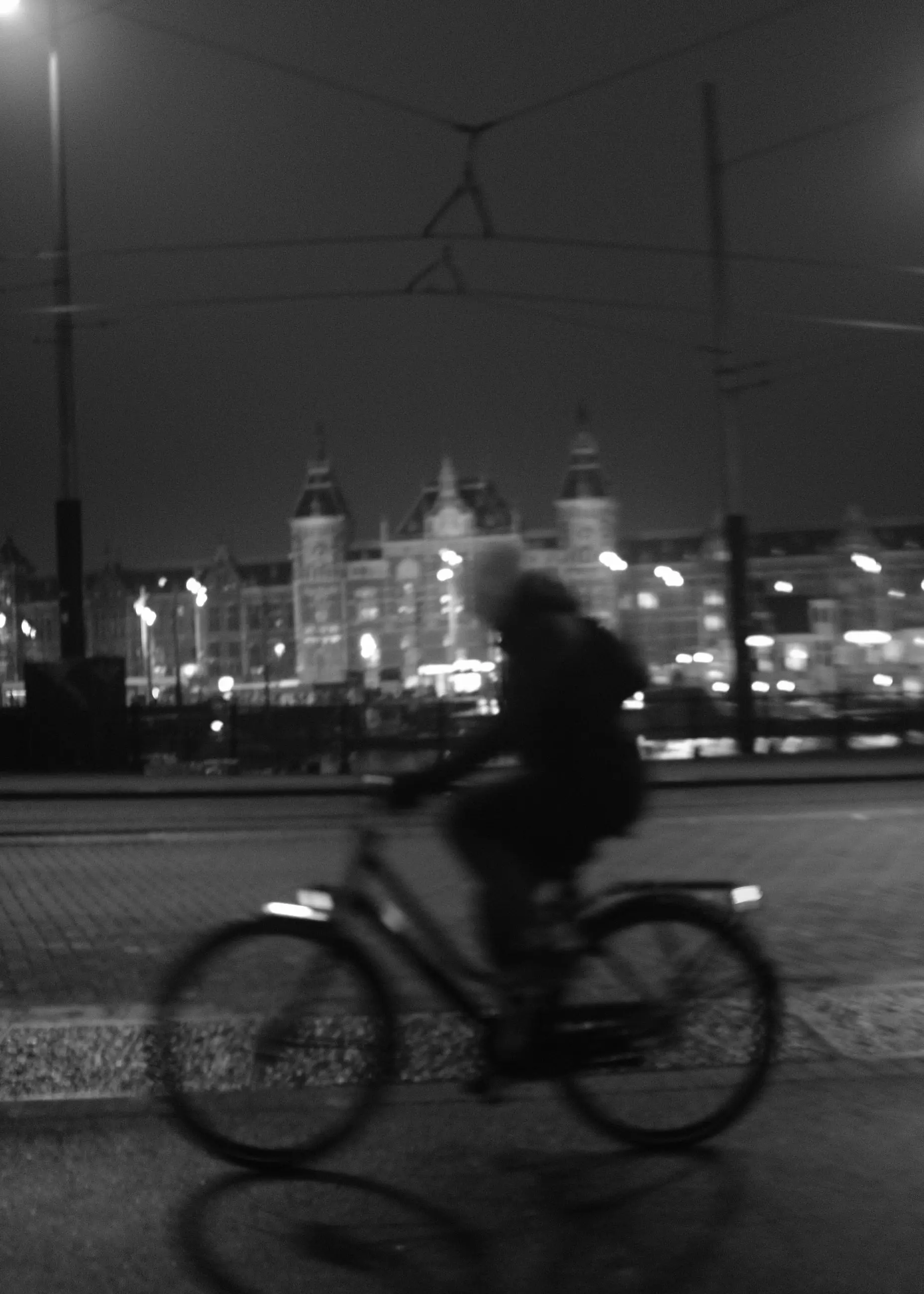 A cyclist in front of Amsterdam Centraal at night