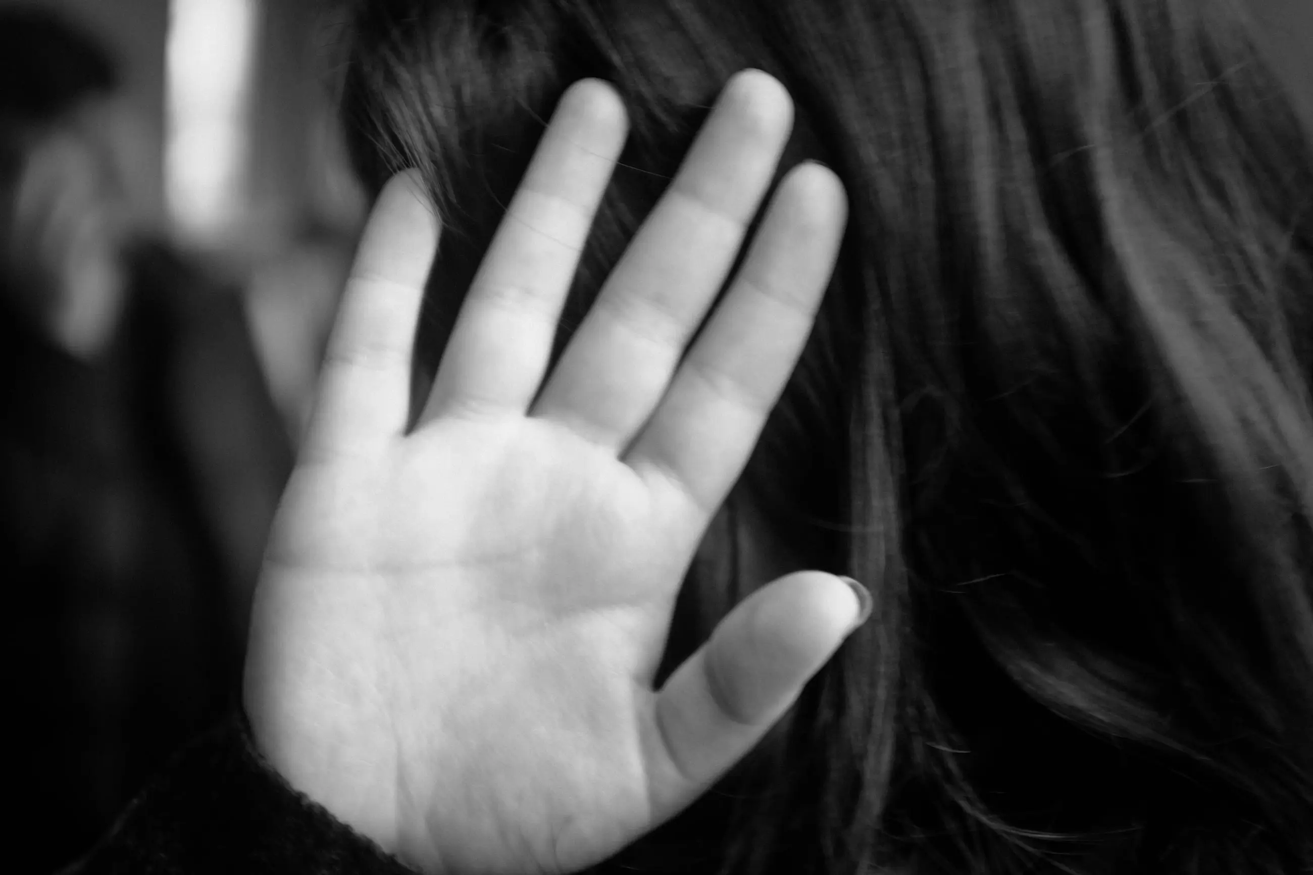 A raised hand in front of a woman's dark hair