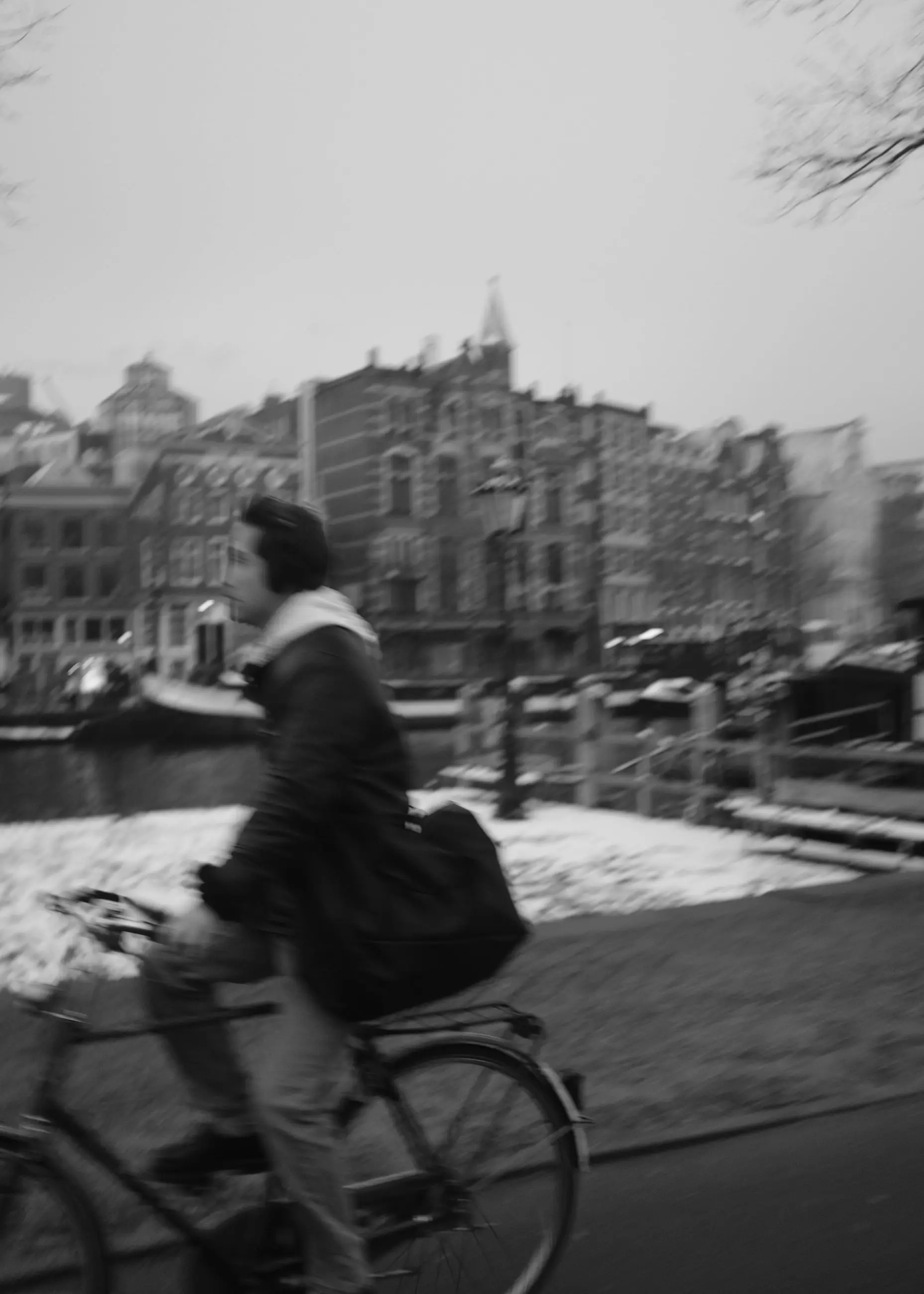 A cyclist in motion in front of canal houses