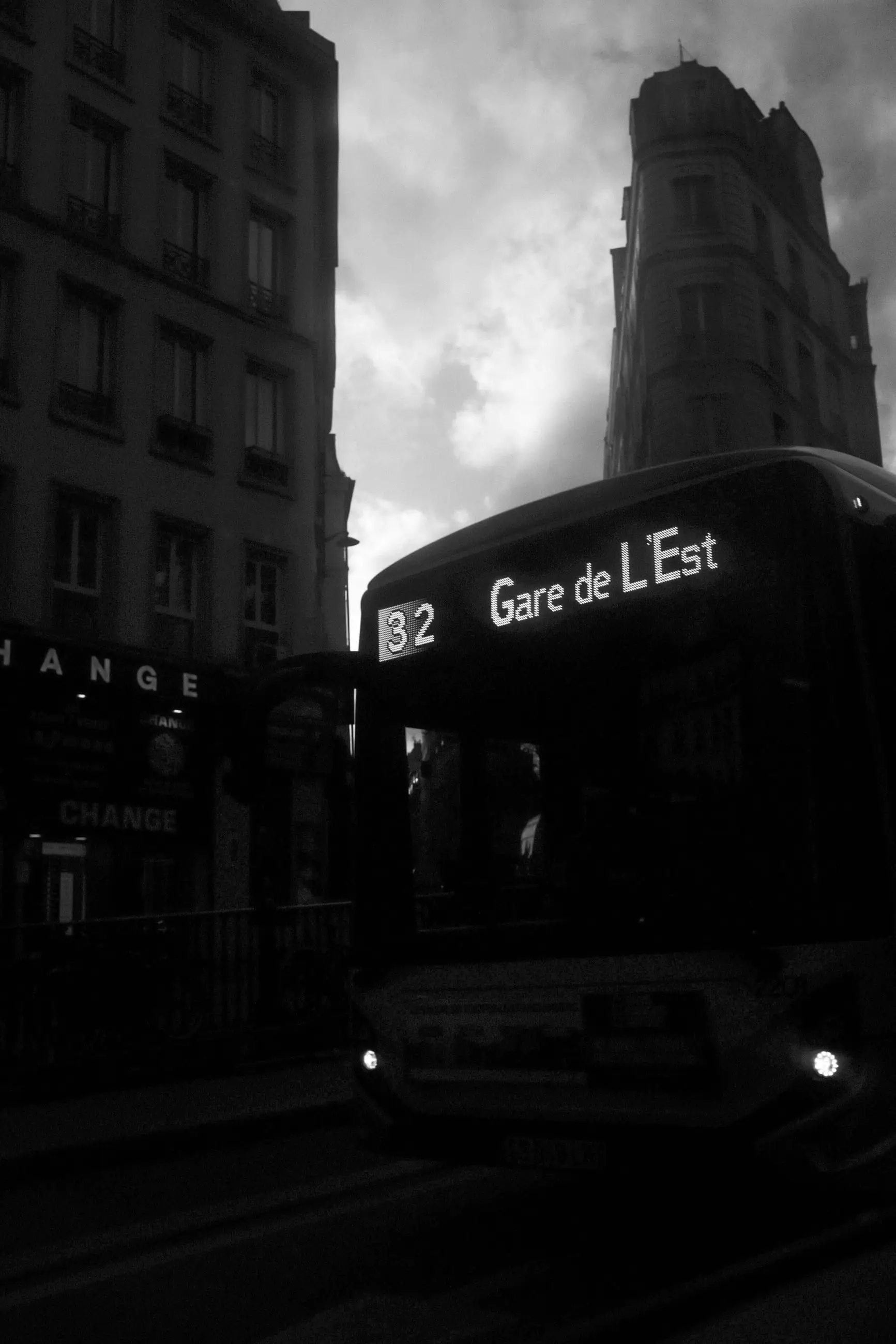 A bus to Gare de l'Est emerging from the dark under a stormy sky