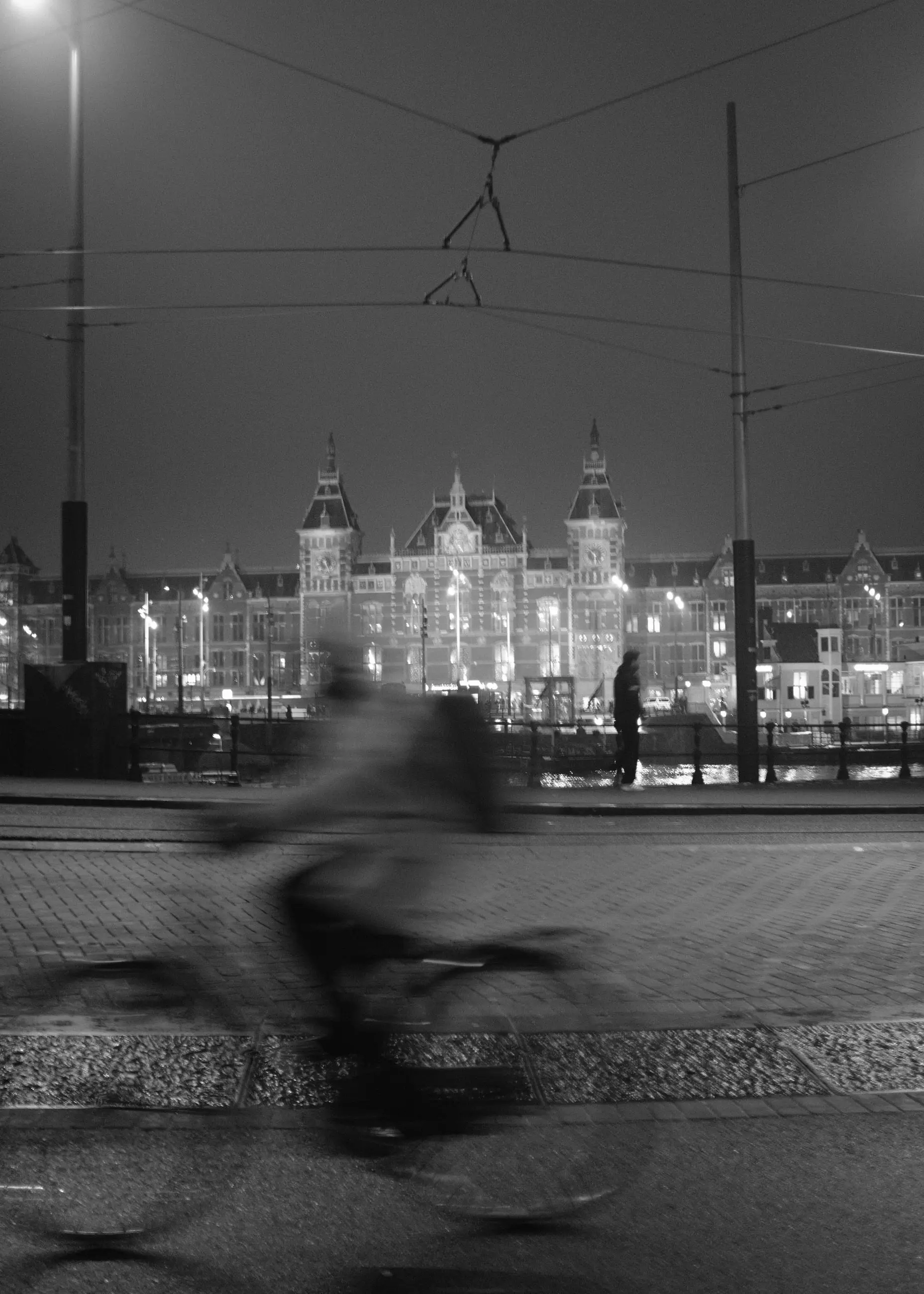 A cyclist in motion, station lights soft behind
