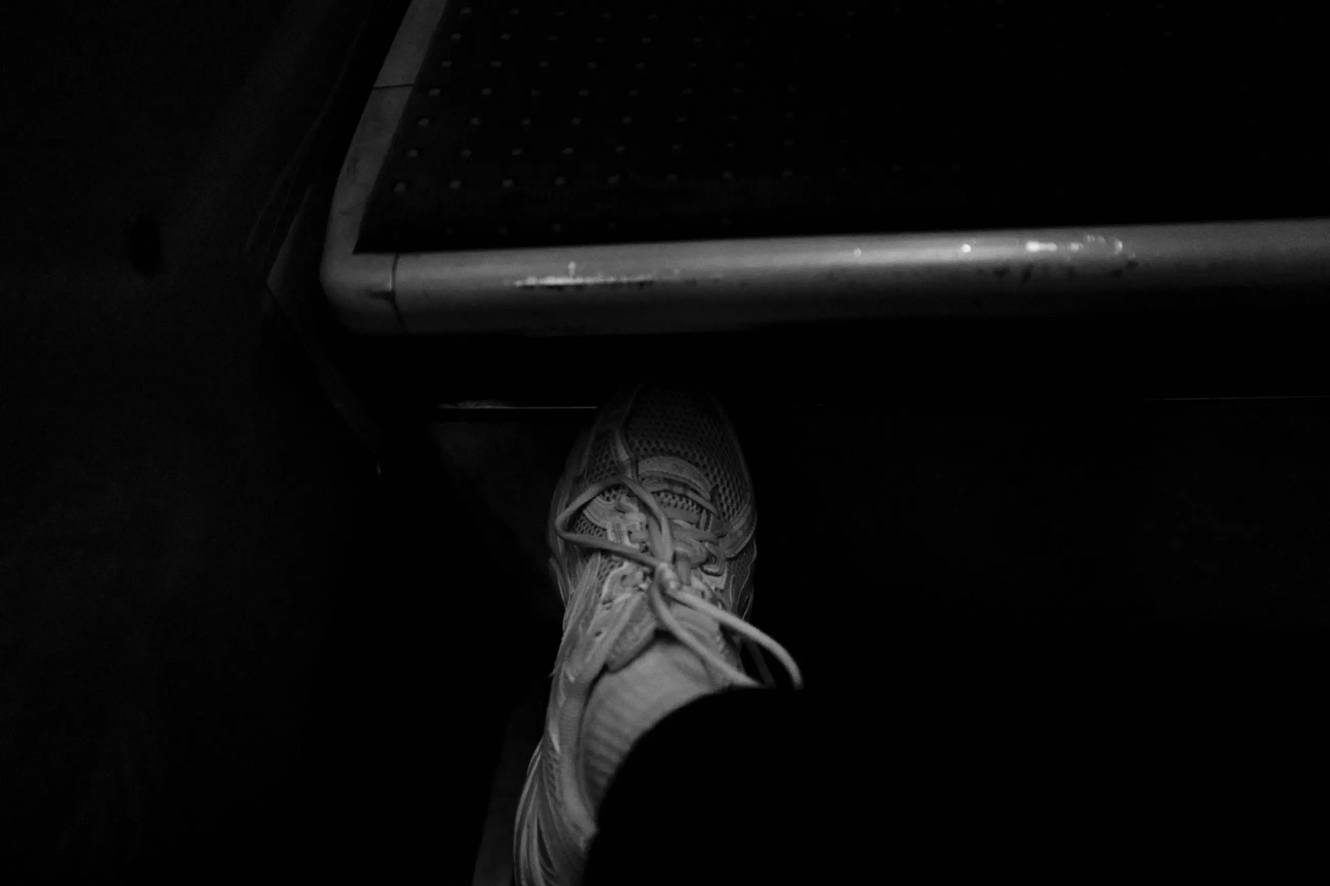 A white sneaker braced against a metro handrail
