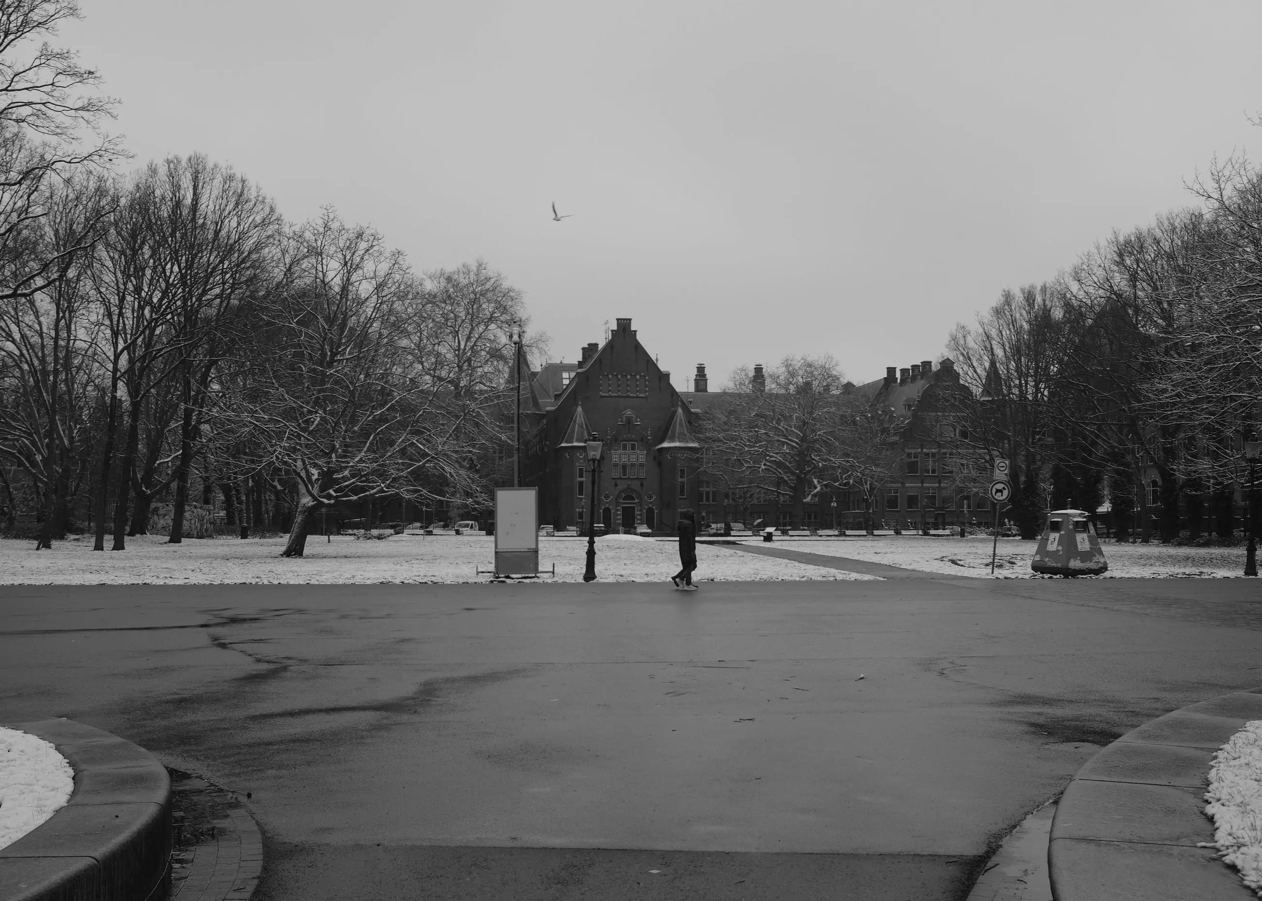 An empty path in the snow, a brick pavilion far away