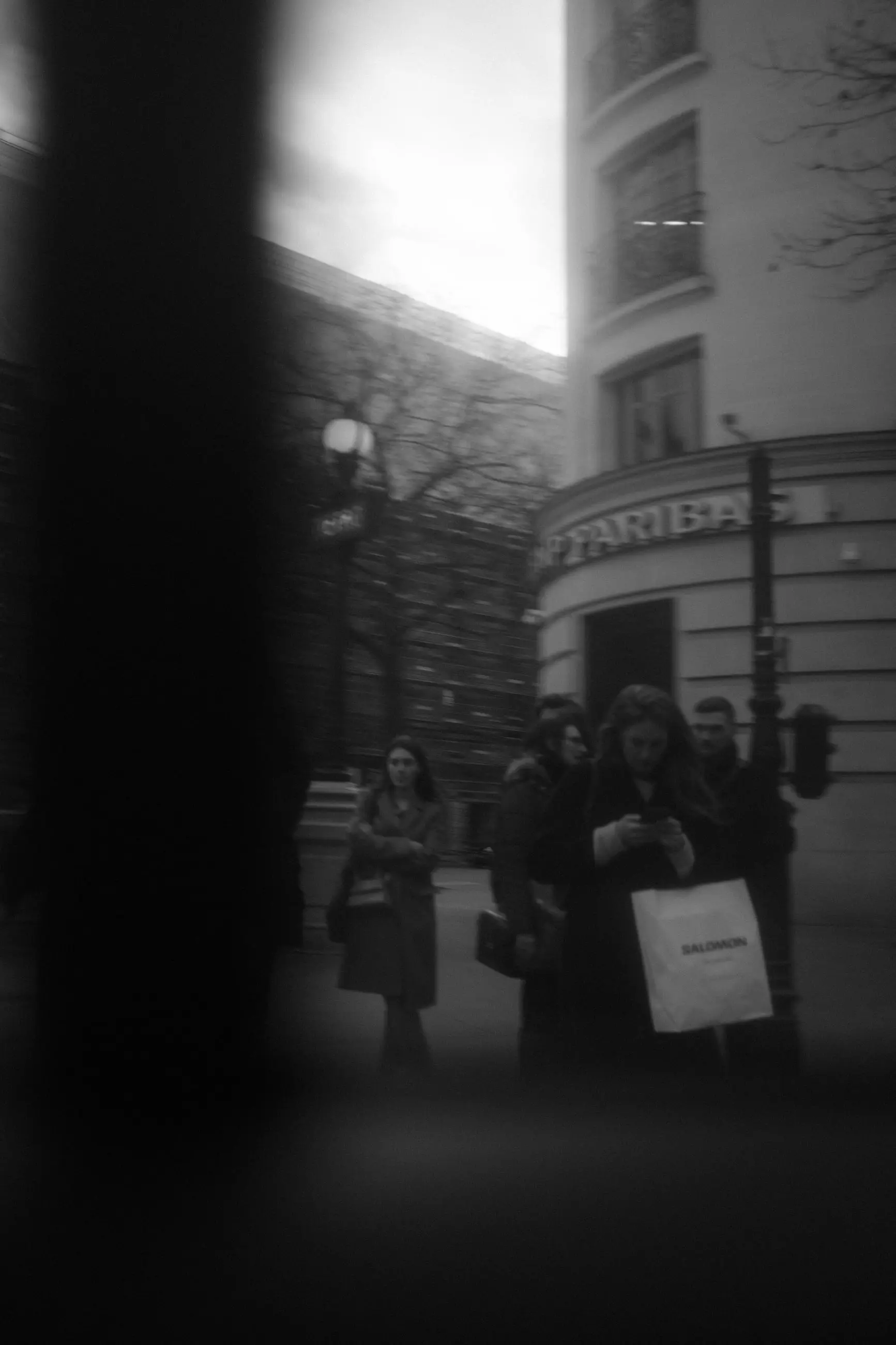 Pedestrians waiting at a corner behind a dark pillar